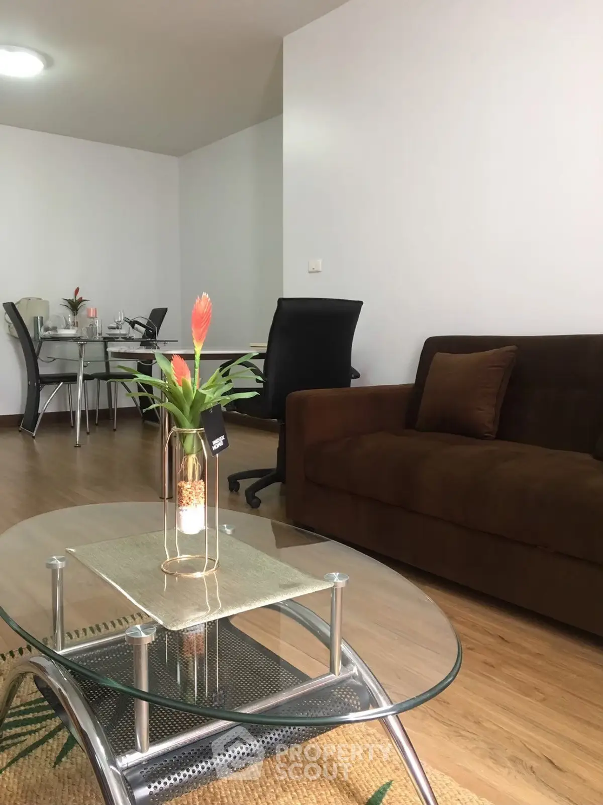 Modern living room with glass coffee table and brown sofa in open layout