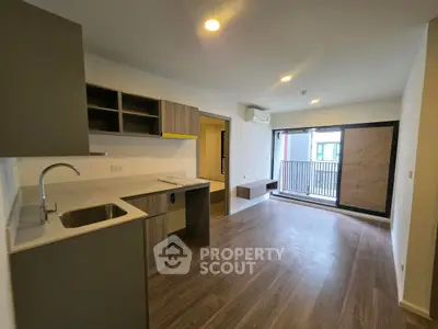 Modern open-plan living room with sleek kitchen and balcony access in stylish apartment.