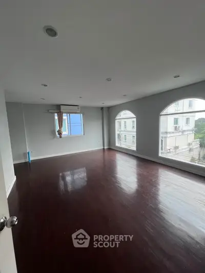 Spacious empty room with large windows and hardwood floors, perfect for customization.