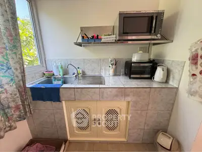 Charming compact kitchen with modern appliances and natural light, perfect for cozy home living.