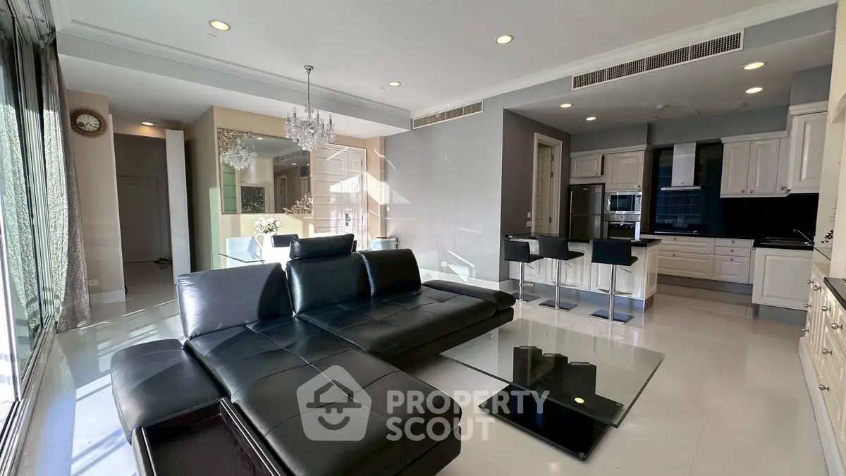 Luxurious modern living room with sleek black leather sofa and open kitchen layout, perfect for entertaining.