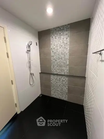 Modern bathroom with sleek tiles and shower area, featuring contemporary design.