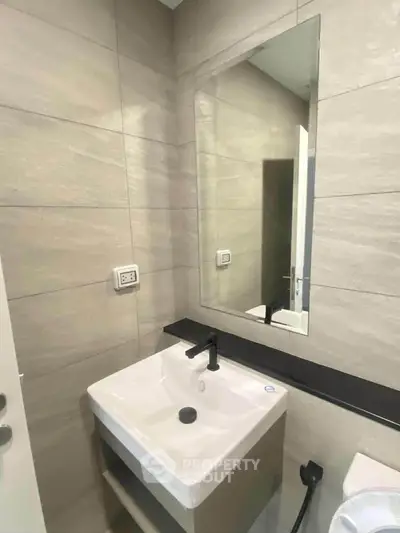 Modern bathroom with sleek sink and large mirror in contemporary design.