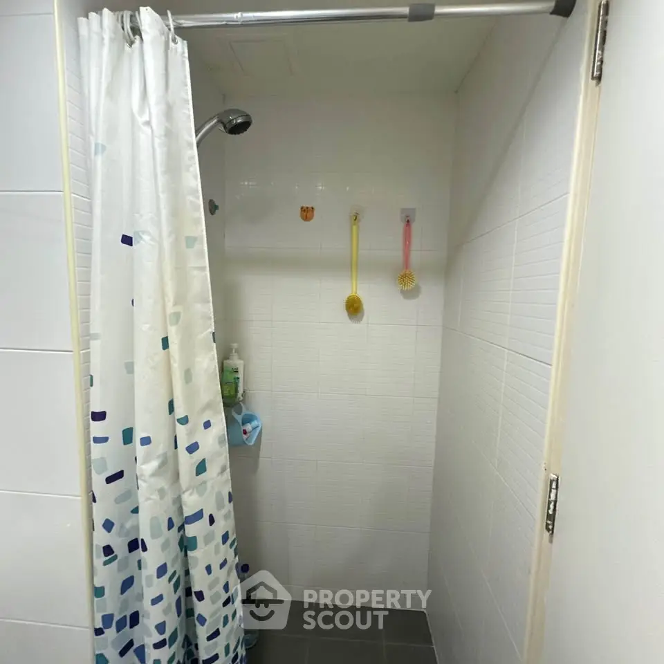 Compact bathroom shower area with curtain and wall-mounted showerhead