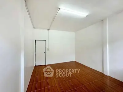Spacious empty room with wooden flooring and white walls, ideal for customization.