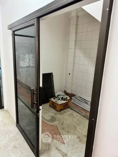 Spacious storage area with glass door and tiled walls, ideal for organizing household items.