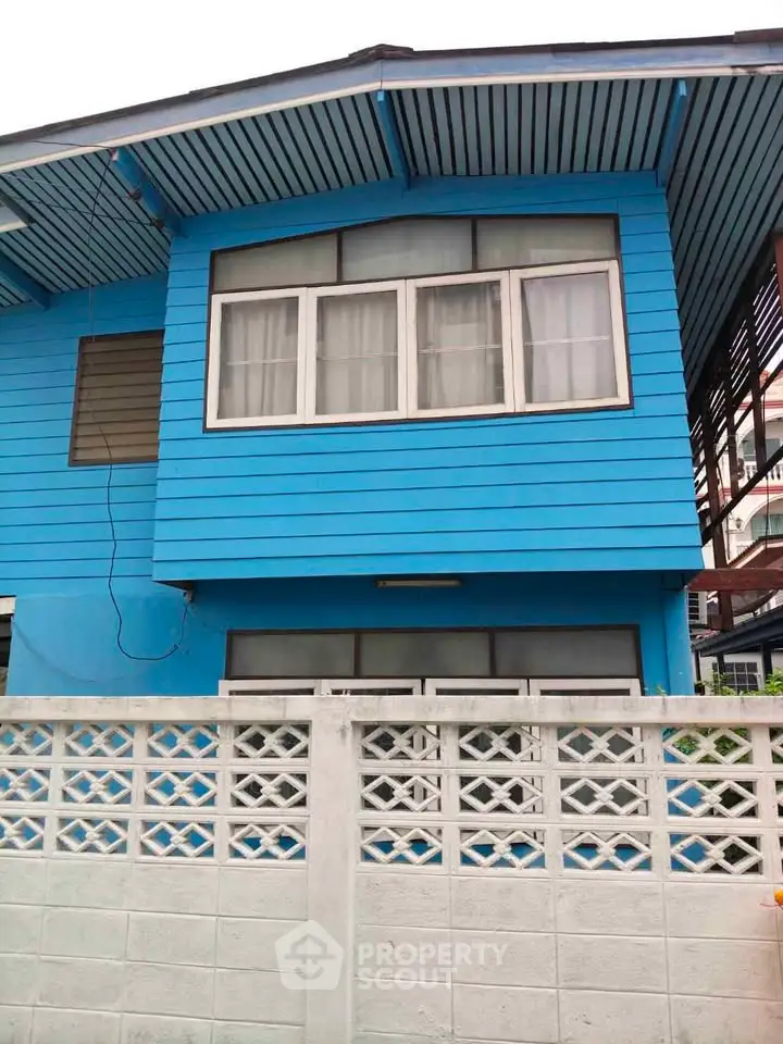 Charming blue wooden house exterior with white fence and large windows.