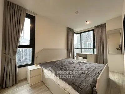 Modern bedroom with large windows and city view, featuring a stylish bed and elegant curtains.