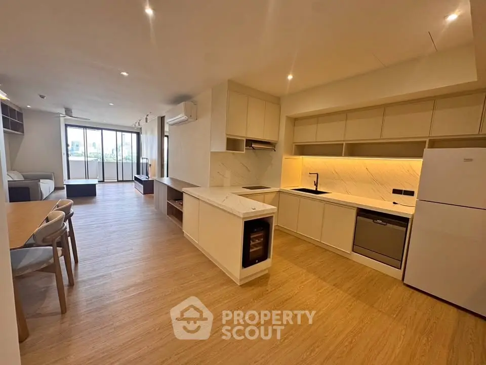 Spacious open-layout kitchen and living area with modern appliances and elegant wooden flooring.