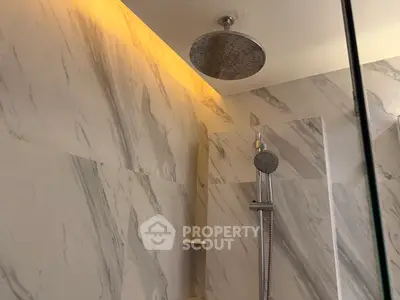 Luxurious marble bathroom with modern rainfall showerhead and ambient lighting