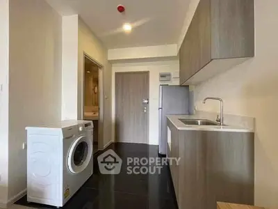 Modern kitchen with washing machine and sleek cabinetry in compact layout.