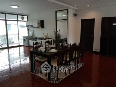 Spacious dining area with elegant wooden furniture and open kitchen layout in modern apartment.