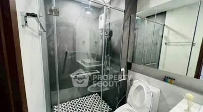Modern bathroom with glass shower enclosure and stylish black and white tiles.