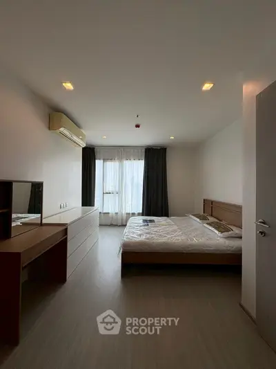 Spacious bedroom with modern furnishings and large window for natural light.