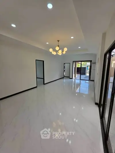 Spacious modern living room with elegant lighting and glossy tiled floors, perfect for family gatherings.