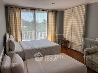 Cozy bedroom with twin beds and large windows offering natural light and garden view.