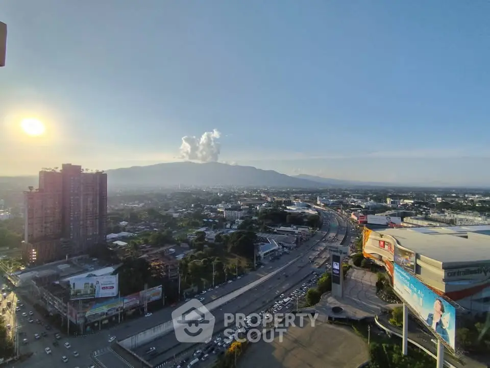Stunning cityscape view from high-rise building with mountains in the background at sunset.