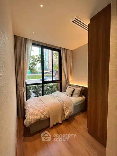 Cozy bedroom with large window and modern decor, perfect for relaxation and comfort.