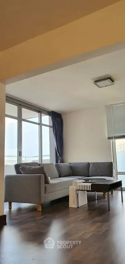 Spacious living room with modern gray sofa and large windows offering natural light.