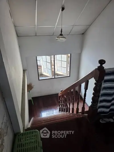 Charming staircase with wooden railing and natural light from window, perfect for cozy home ambiance.