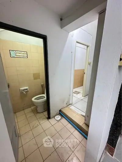 Compact bathroom with tiled floor and basic fixtures in need of renovation.