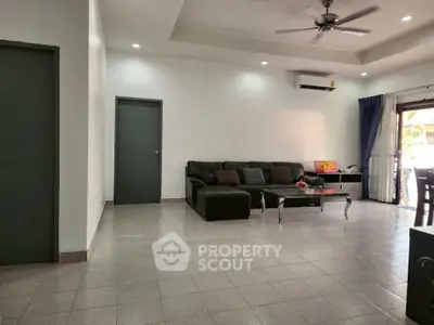 Spacious living room with modern sofa and natural light, ideal for family gatherings.