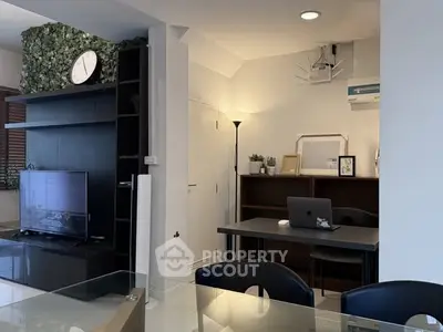 Modern living room with stylish decor and workspace, featuring a TV and air conditioning.