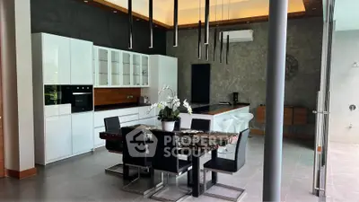 Modern kitchen with sleek white cabinets, dining area, and stylish lighting in a contemporary home.