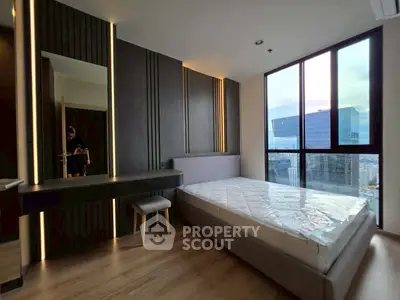 Modern bedroom with floor-to-ceiling windows and city view, featuring sleek design and natural light.