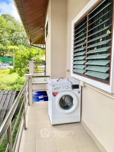 Charming balcony with washing machine and lush green view, perfect for convenient laundry and relaxation.