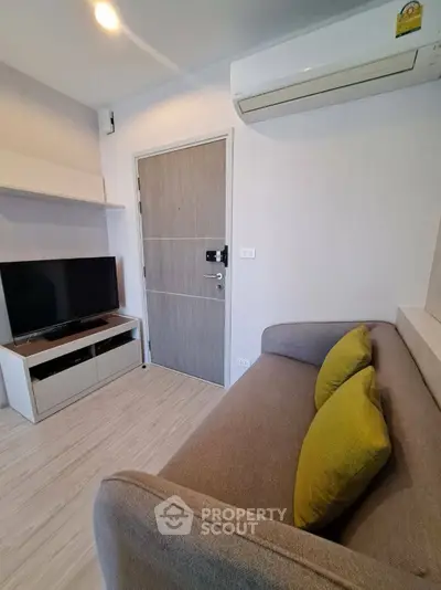 Cozy living room with modern sofa, TV, and air conditioning in a stylish apartment.