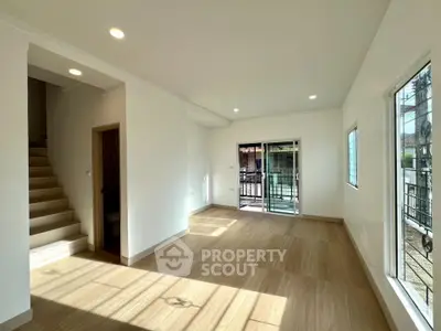 Spacious and bright living room with wooden flooring and large windows in modern home.
