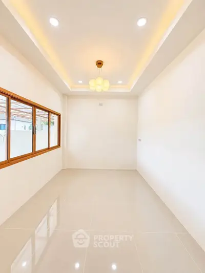 Spacious empty room with modern lighting and large window, perfect for customization.