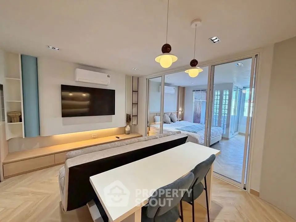Modern open-plan living room with dining area and bedroom, featuring stylish decor and ample natural light.