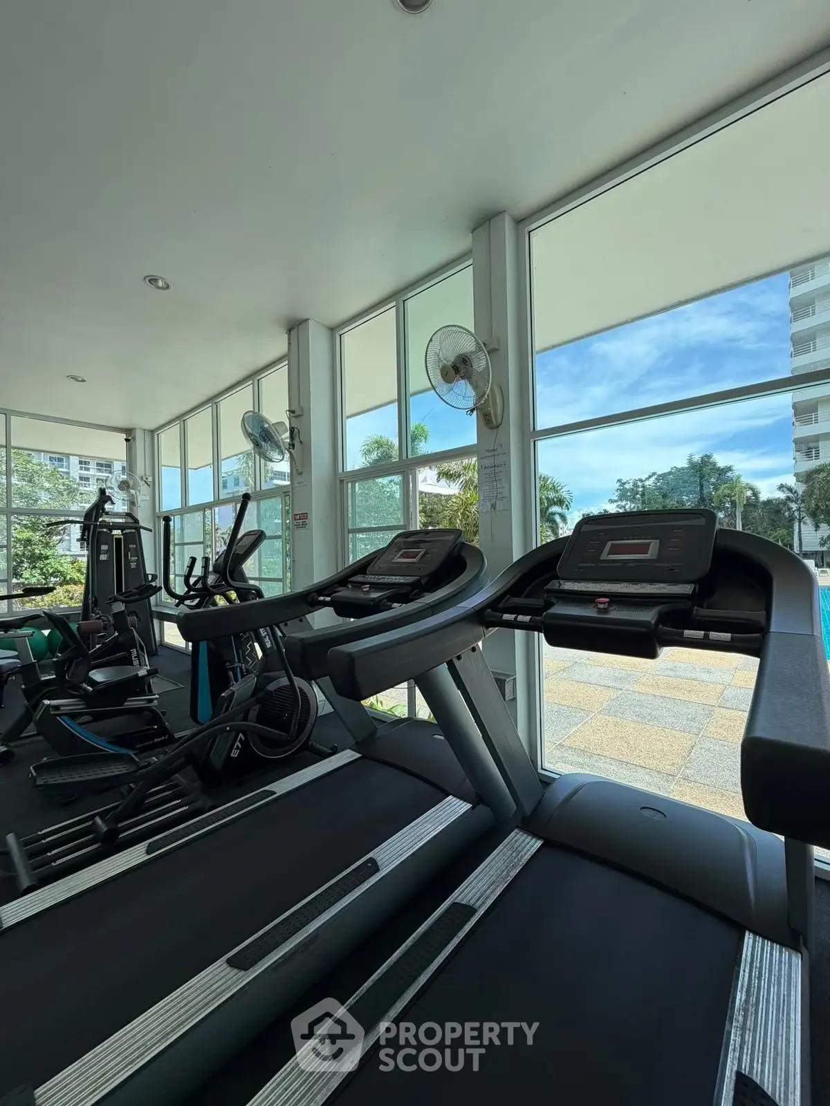 Modern gym with large windows offering a scenic view, equipped with treadmills and exercise machines.