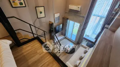 Modern loft apartment with stylish living room and mezzanine bedroom, featuring large windows and elegant decor.