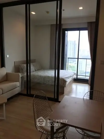 Modern apartment with glass partitioned bedroom and city view balcony.