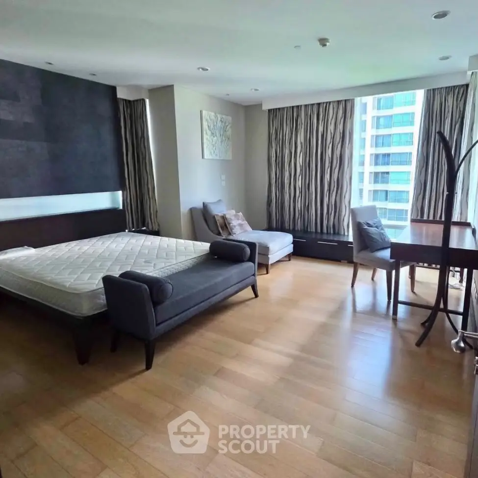 Spacious bedroom with modern decor and large windows in a high-rise apartment.