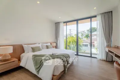 Spacious bedroom with large windows and modern decor, offering a serene view of the neighborhood.