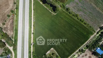 Aerial view of expansive green land beside a highway, ideal for development opportunities.
