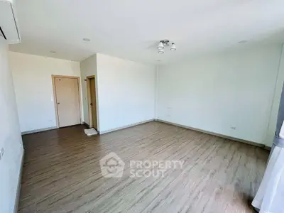 Spacious empty room with wooden flooring and modern lighting, perfect for customization.