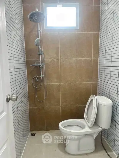 Modern bathroom with sleek shower and toilet, featuring stylish tile design.