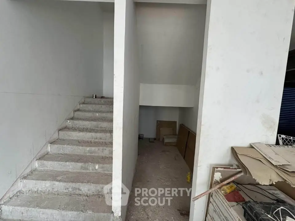 Unfinished interior space with concrete stairs and storage area, ideal for customization.