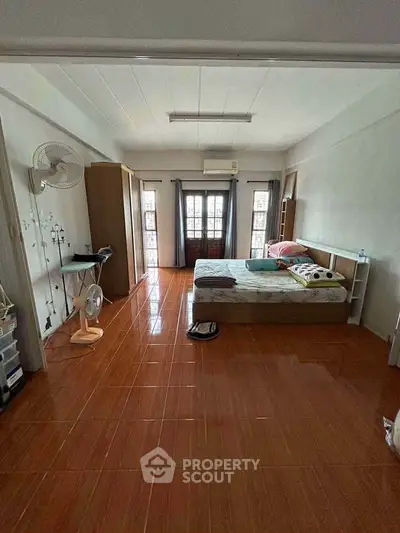 Spacious bedroom with natural light and tiled flooring, featuring a bed, wardrobe, and desk.