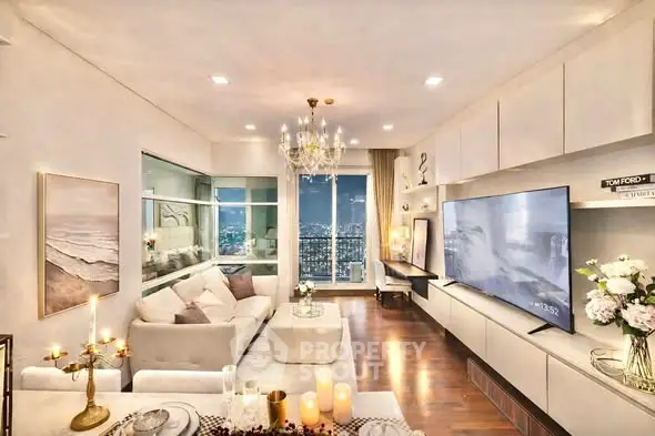 Luxurious living room with elegant decor and stunning city view, featuring a large TV and chandelier.
