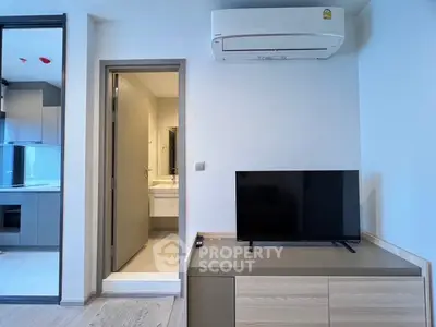 Modern apartment interior with TV, air conditioning, and view into bathroom.