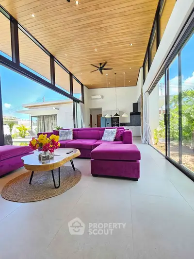 Stunning modern living room with high ceilings, vibrant purple sofa, and expansive windows offering natural light.