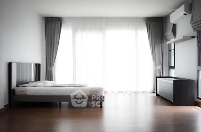 Spacious modern bedroom with large windows and elegant furnishings.