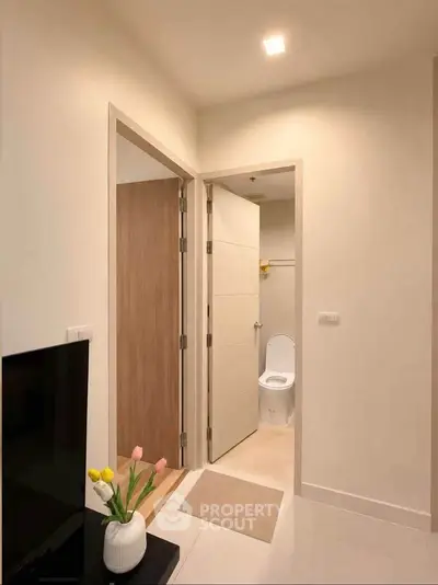 Modern apartment interior with view into bathroom, featuring sleek design and neutral tones.