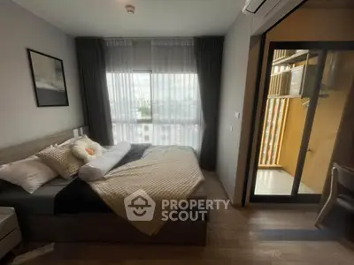 Cozy bedroom with large window and balcony access, featuring modern decor and ample natural light.
